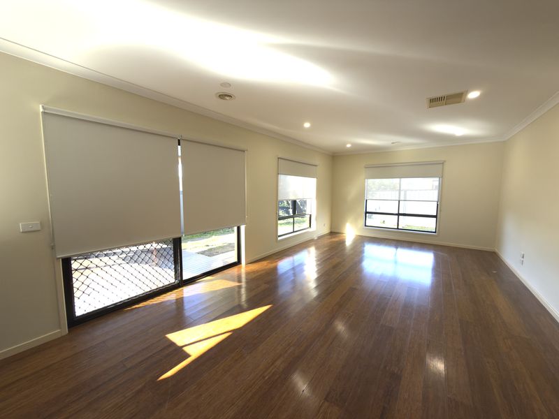 Light-filtering roller blinds fitted across sliding doors and windows in a bright Melbourne living room